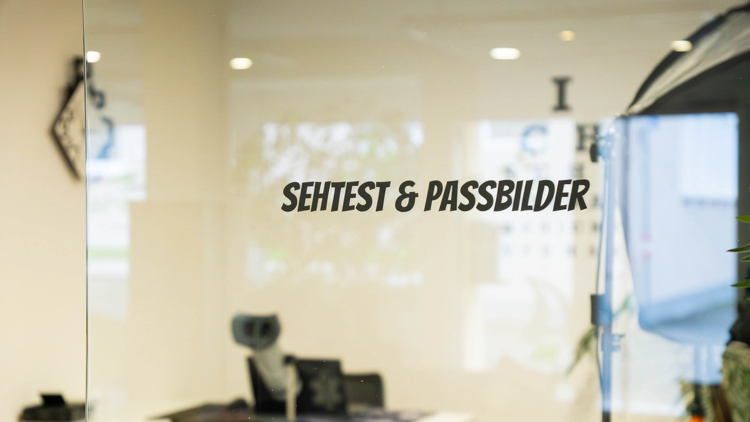 Fahrschule Fahrwerk Bayer GmbH - Führerscheinausbildung - Eine Glasfläche signalisiert, dass die Einrichtung Sehtests und Passfotos anbietet.