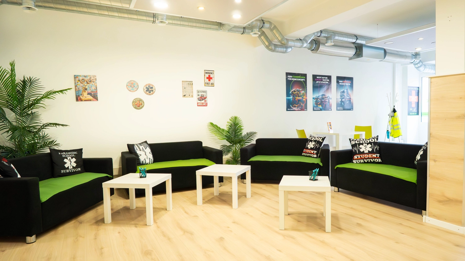 Fahrschule Fahrwerk Bayer GmbH - Führerscheinausbildung - Ein weißes Regal mit verschiedenen Gegenständen, darunter Pflanzen und Zapfen, neben einem schwarzen Sofa.