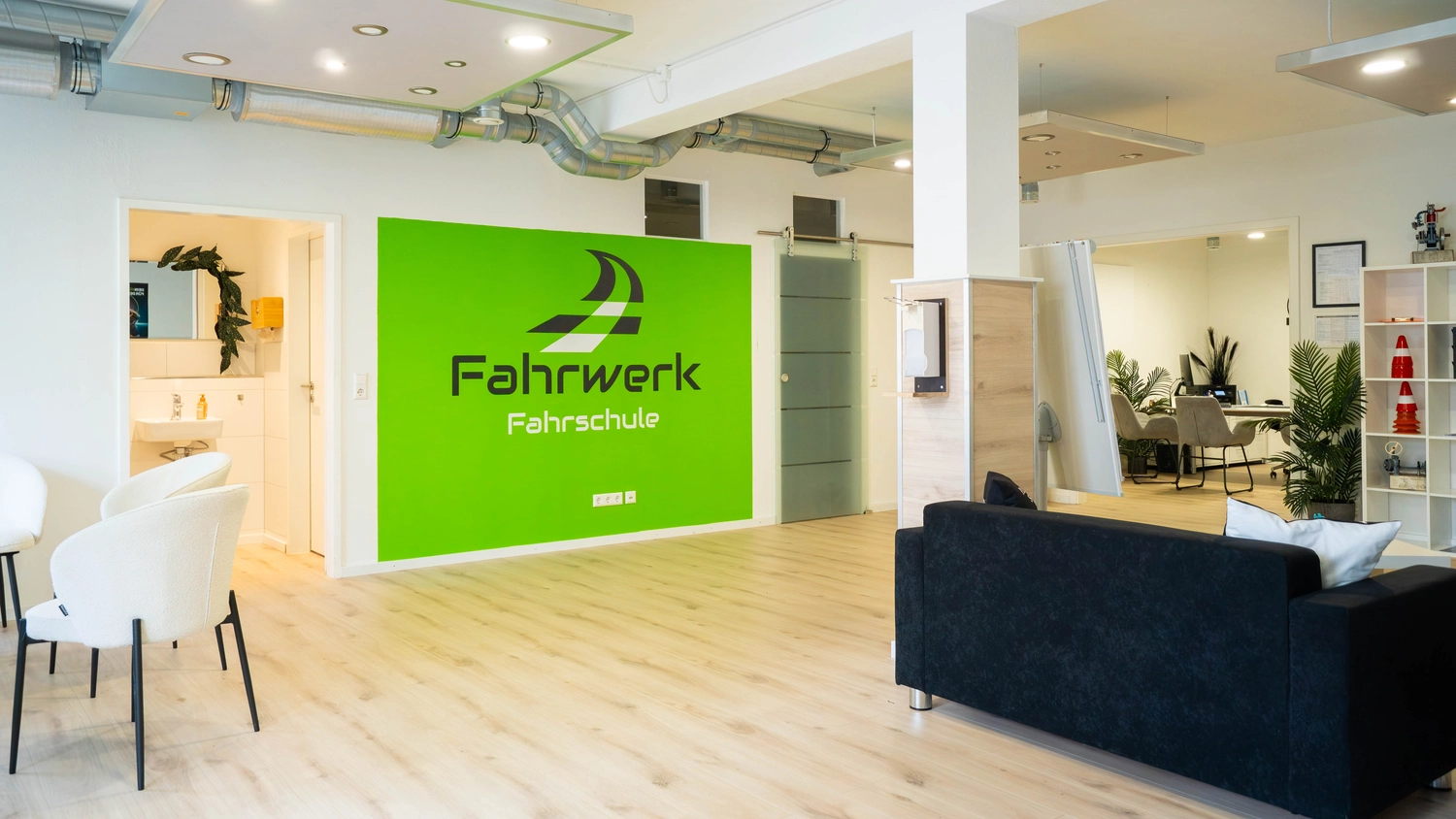 Ein moderner Wartebereich mit schwarzen Sofas, weißen Couchtischen und Stühlen.